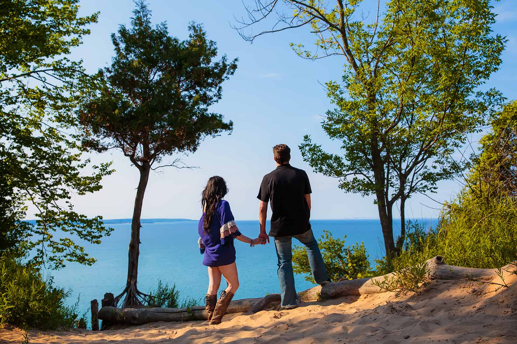 Couple on sand dunes at sunset overlooking lake