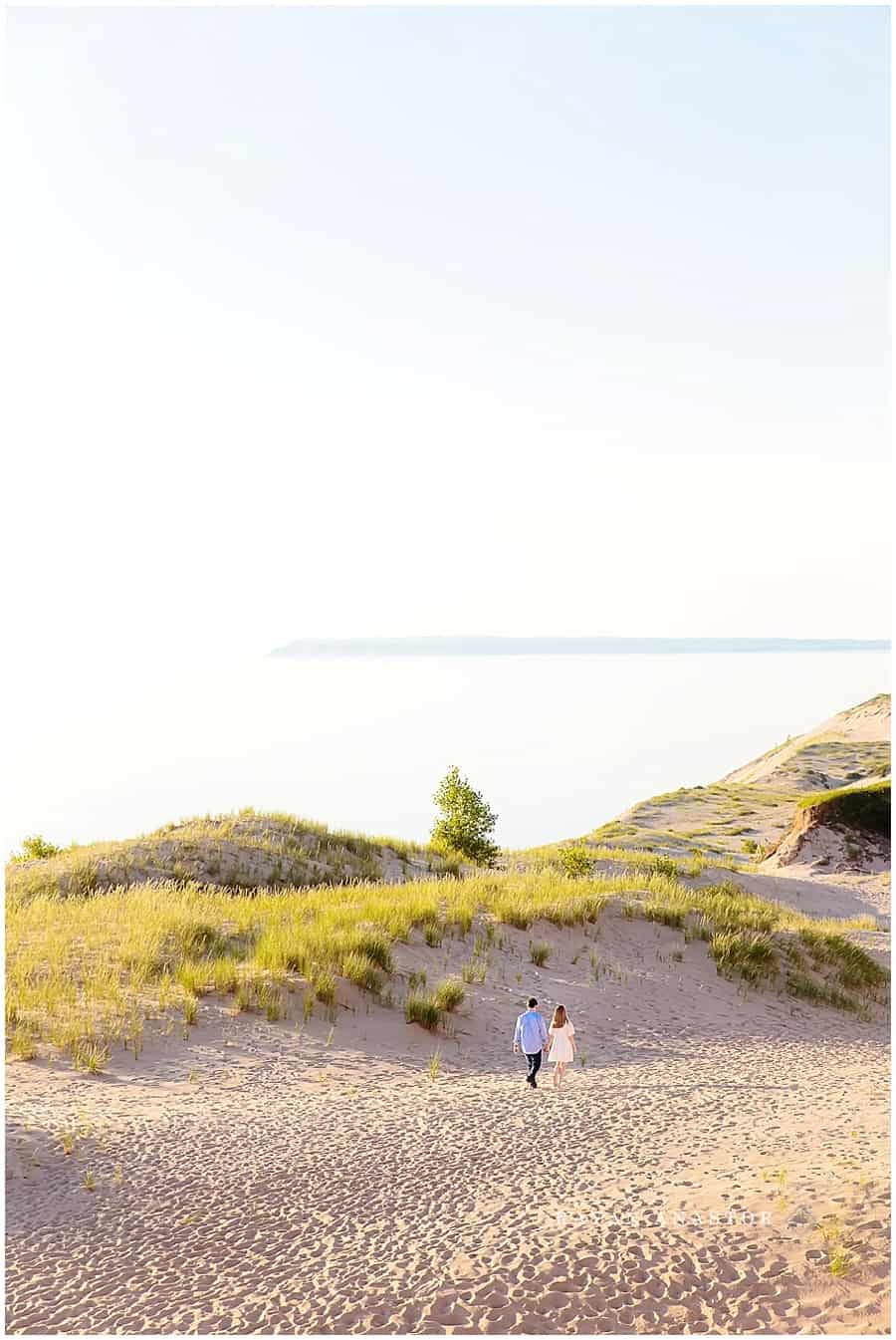 engagement photo of couple walking through sand dunes