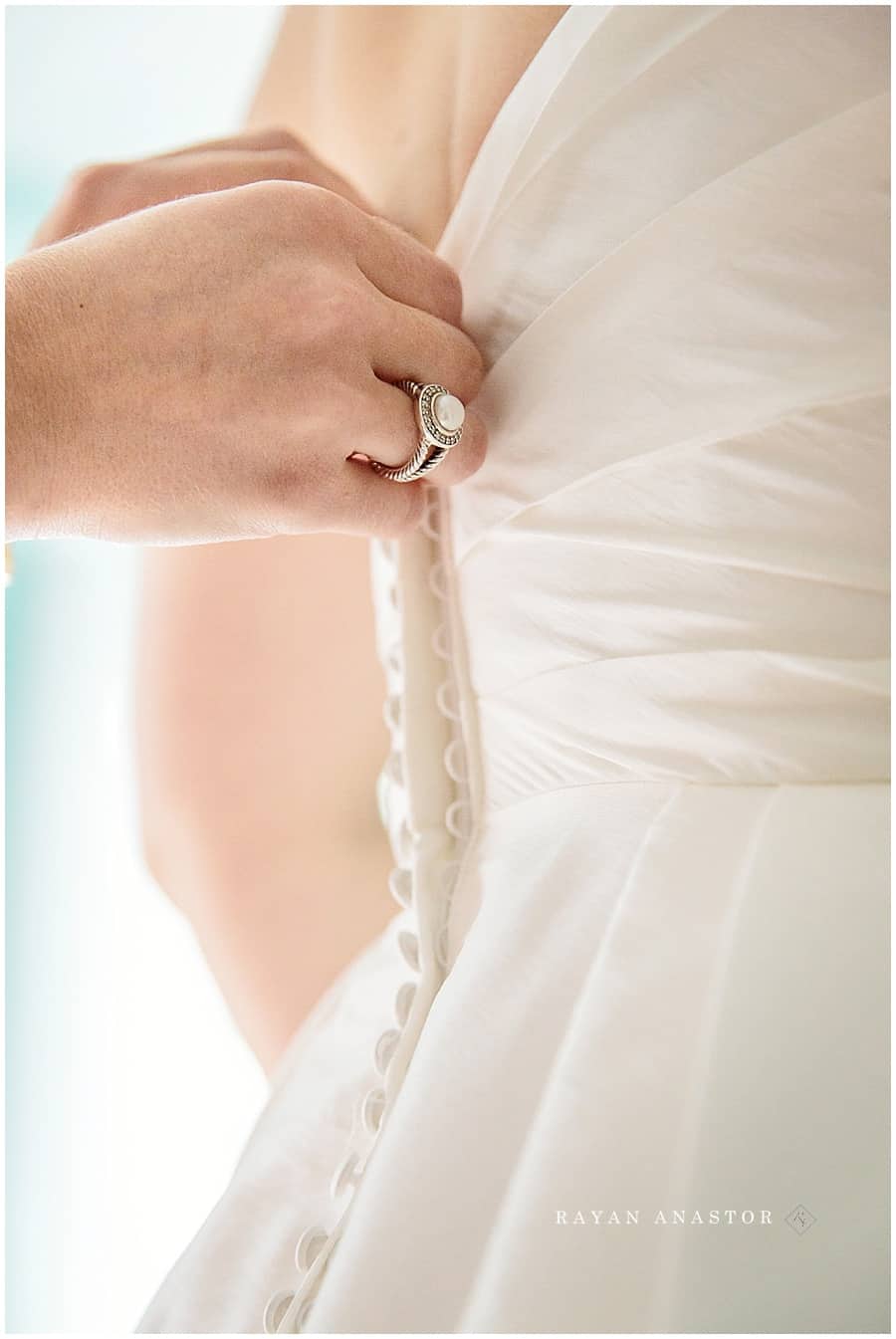 bride having her dress buttoned up at the red shutter