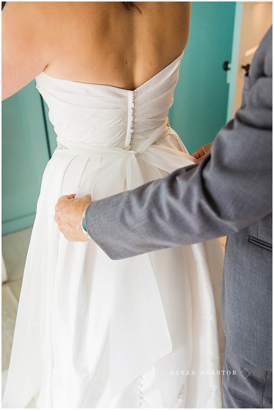 dad tying the brides bow after getting dressed