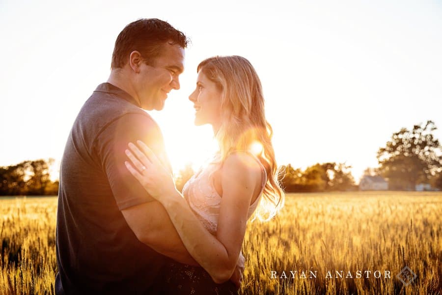 couple at sunset in wheat field with sun shining through