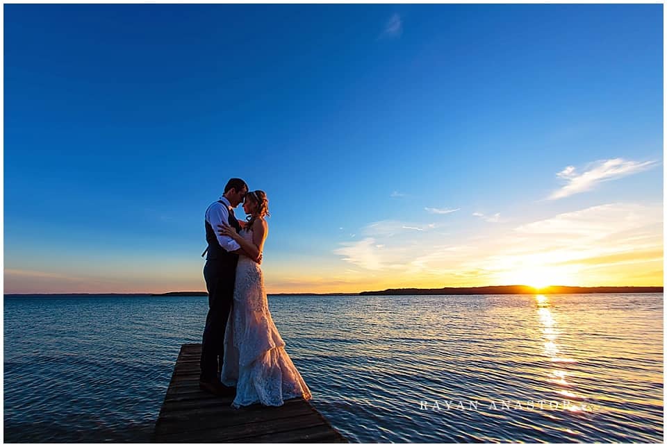 Bride and Groom on dock overlooking Traverse City at Sunset