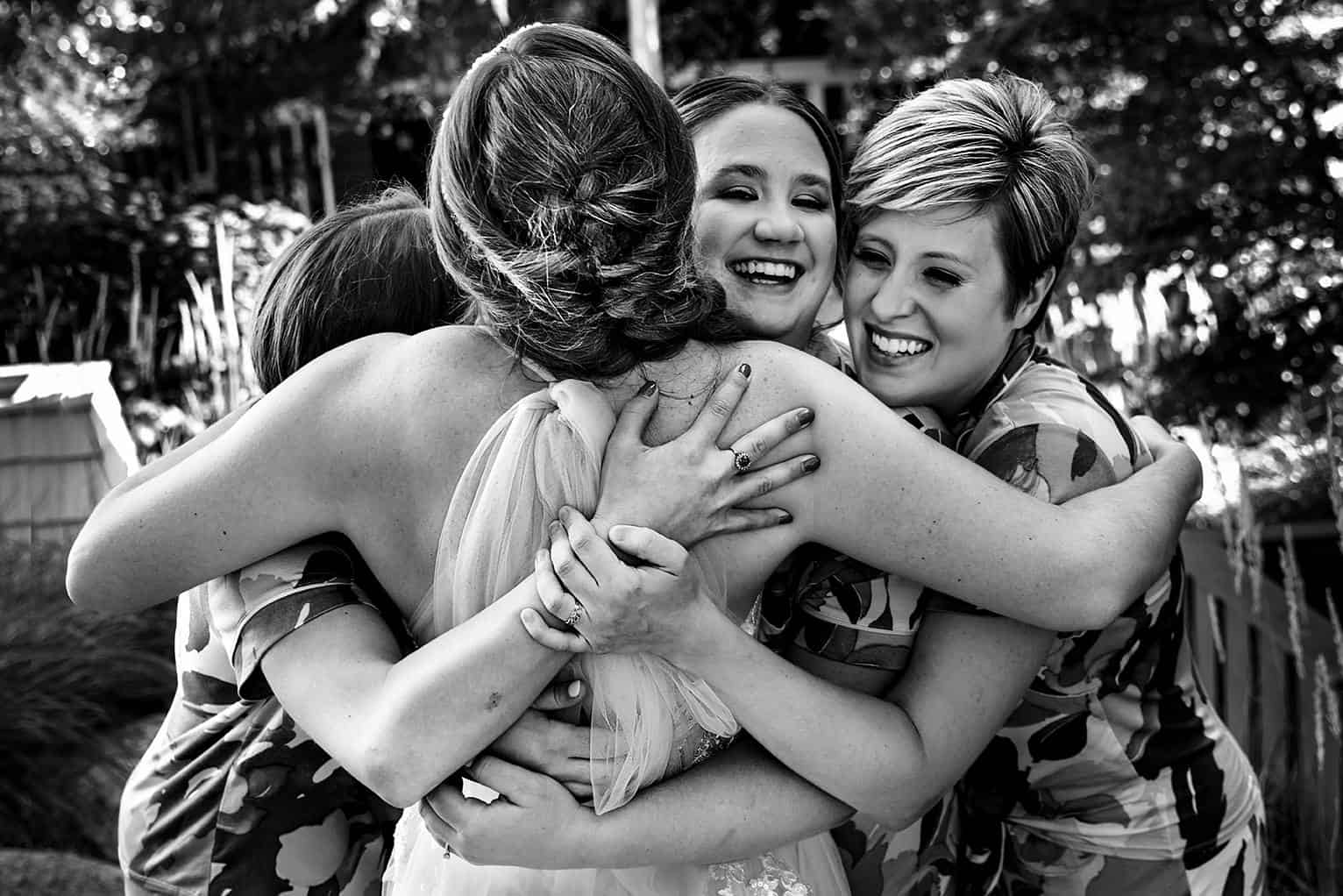 bridesmaids hugging bride at iron fish distillery