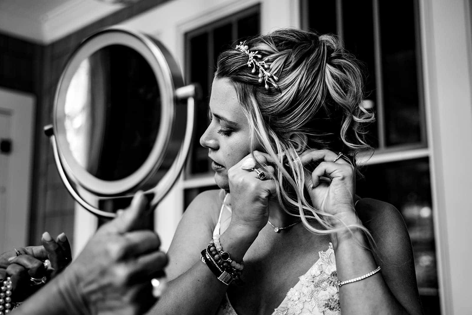bride putting on earring with mom