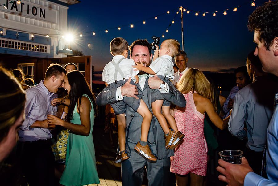 Ring bearers dancing with groom at night under twinkle lights
