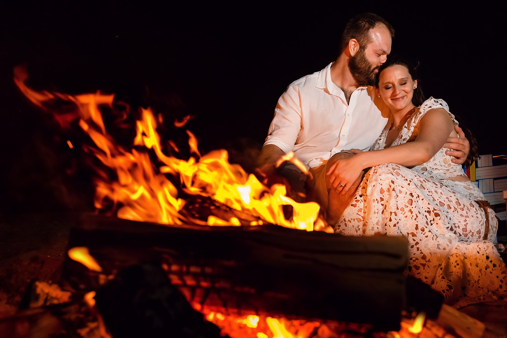 Bride and Groom at bonfire on beach after wedding