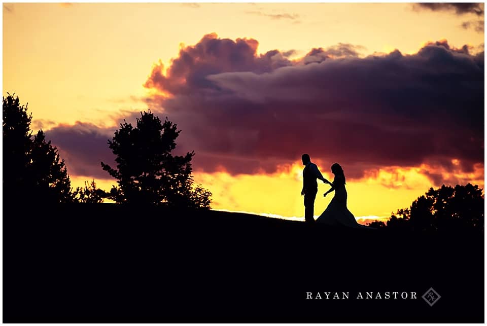 bride and groom walking up a hill at sunset
