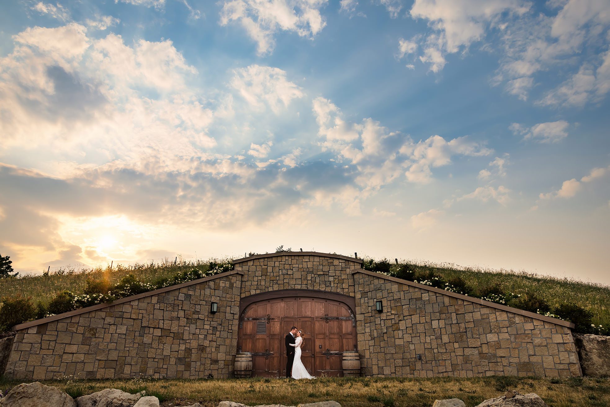bride and groom in front of cave door at Mari Vineyard at sunset