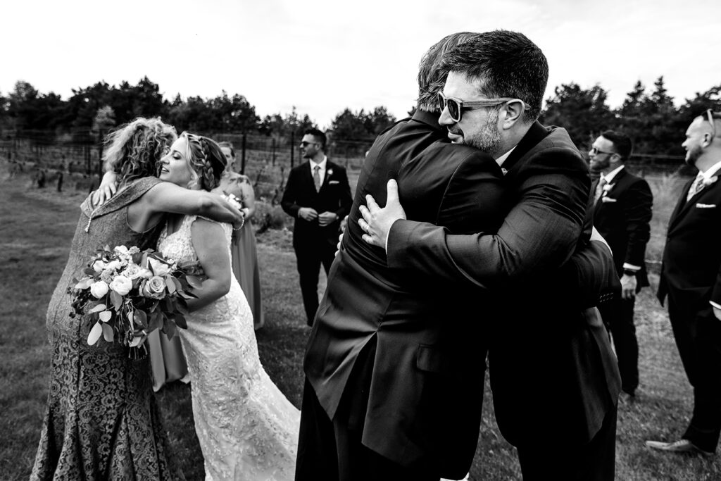 Bride and groom hugging parents after wedding
