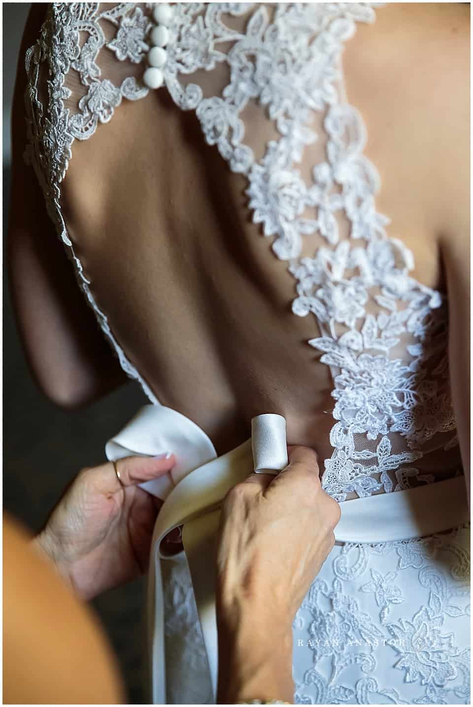 Mom tying bow on daughters wedding gown by aurora unique bridal boutique