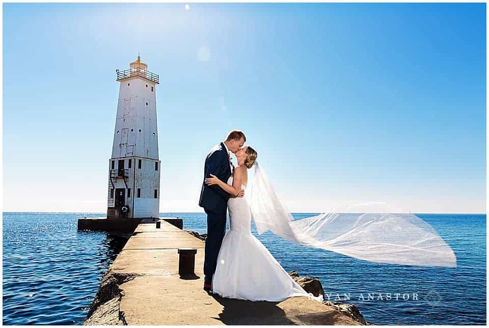 Bride and Groom on pier at Frankfort Lighthouse on lake michigan