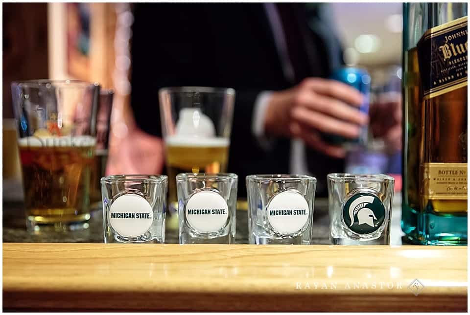 groom toasting with michigan state university shot glasses