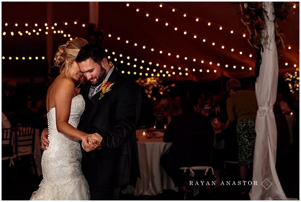 wedding reception with string lights and candles in tent on private residence