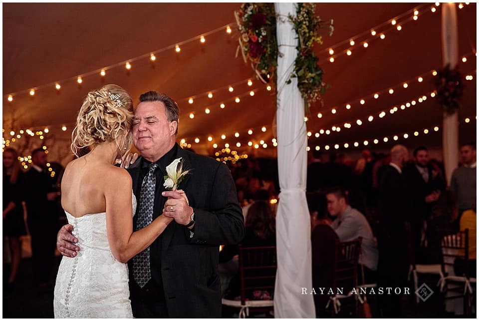 wedding reception with string lights and candles in tent on private residence