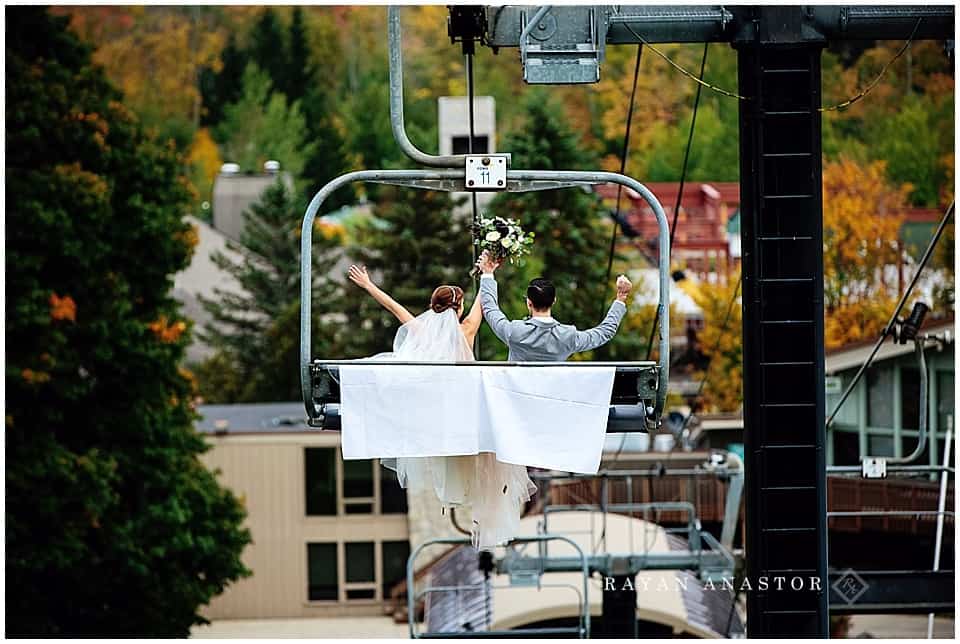 bride and groom riding down ski lift after wedding