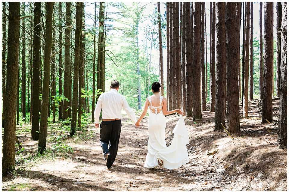 bride and groom walking through a pine forest