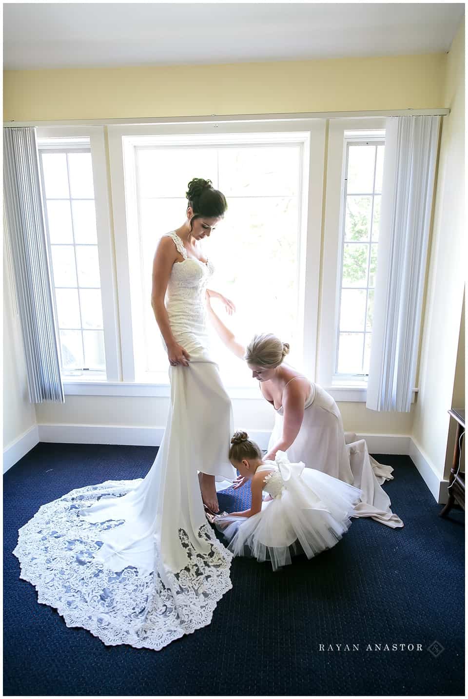 maid of honor and daughter putting shoes on bride