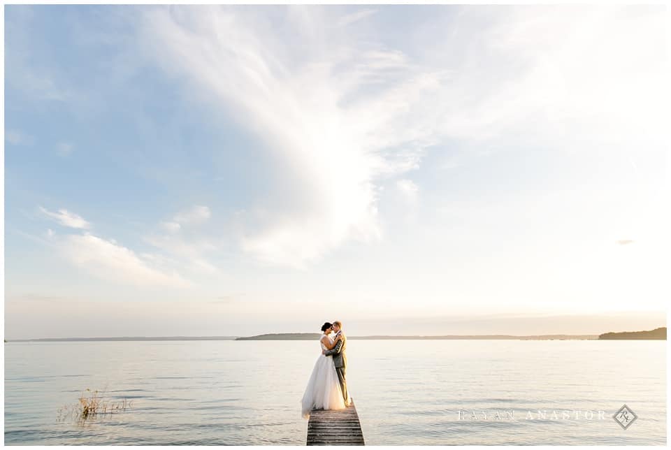 Bride and Groom on dock over water at sunset