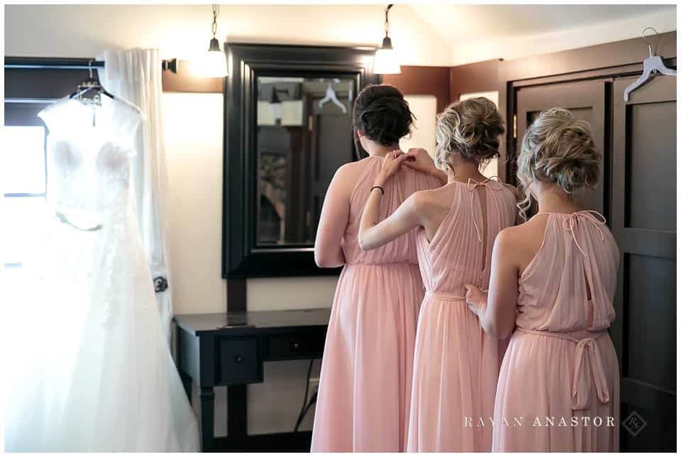 bridesmaids getting dressed in pink dresses