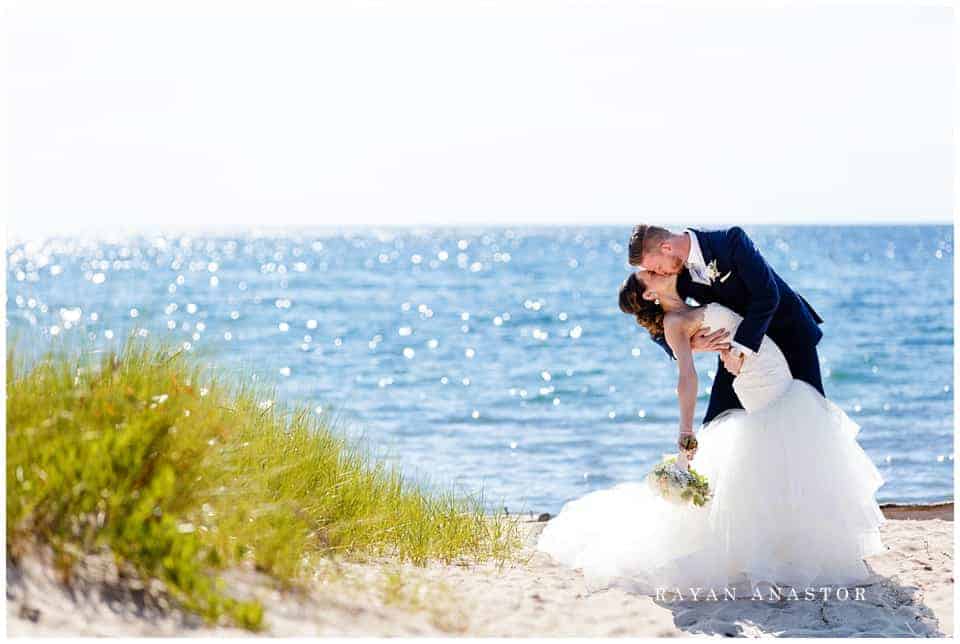 Groom dipping bride on lake michigan