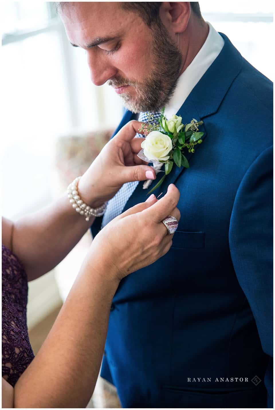 mom placing boutonnière on son before wedding