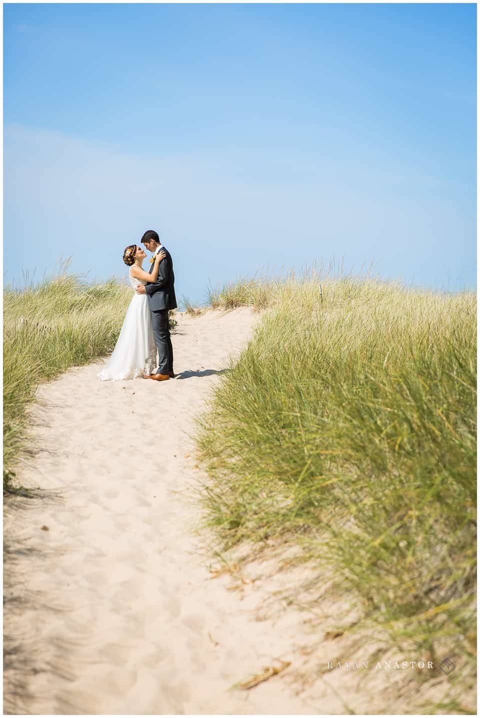 bride and groom on sand walkway to lake michigan