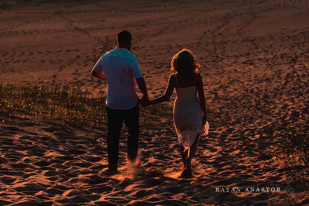 Bride and Groom running through the sand at sunset