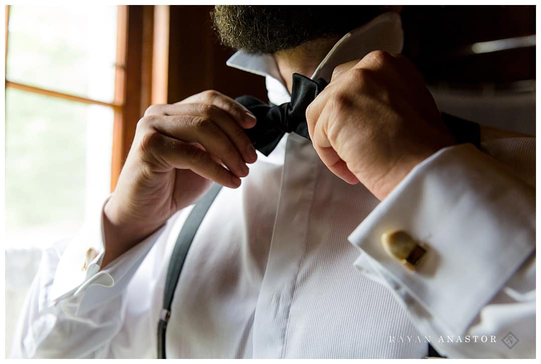 groom tying bowtie