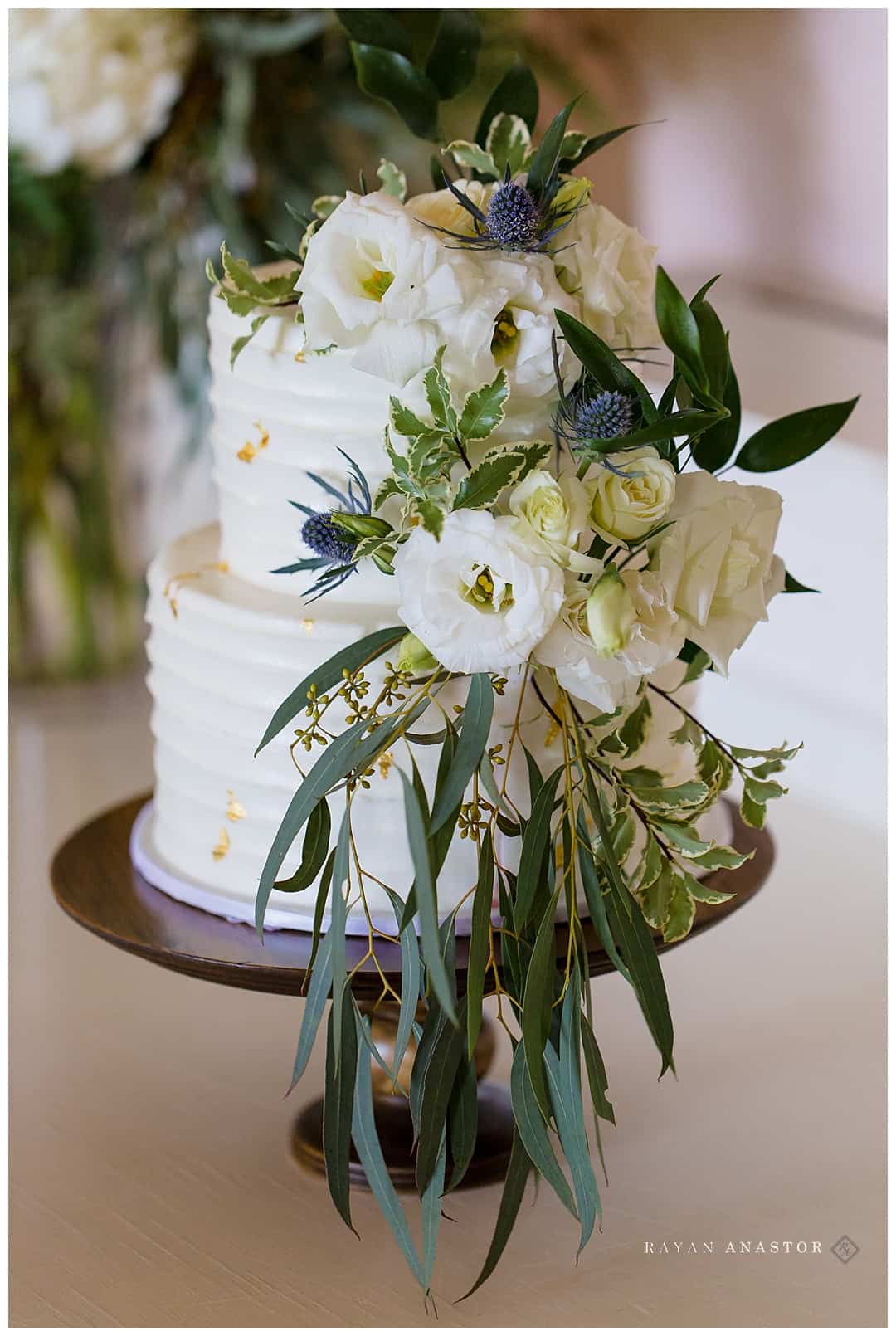 white and gold wedding cake with green and white florals
