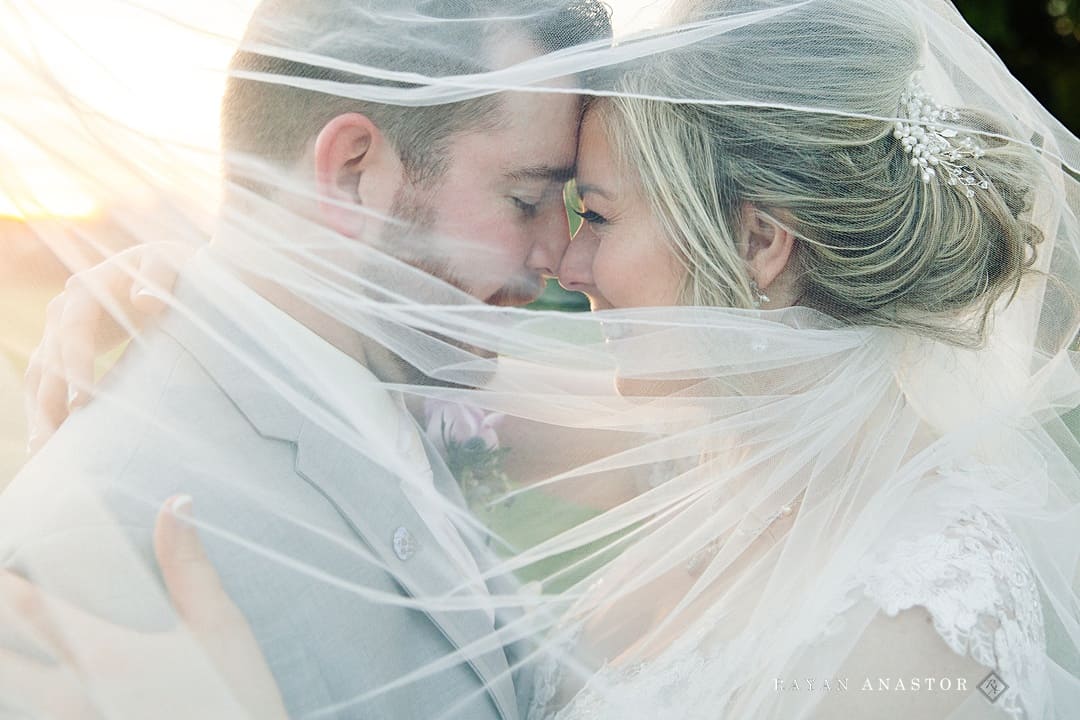 bride and groom under veil at sunset