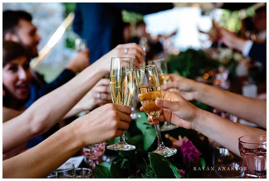Wedding guests toasting over farm table