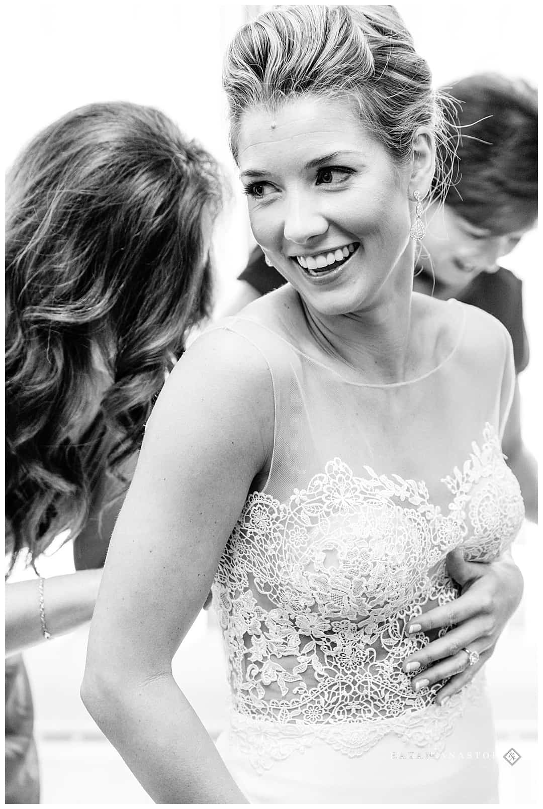 bride laughing while getting dressed for wedding