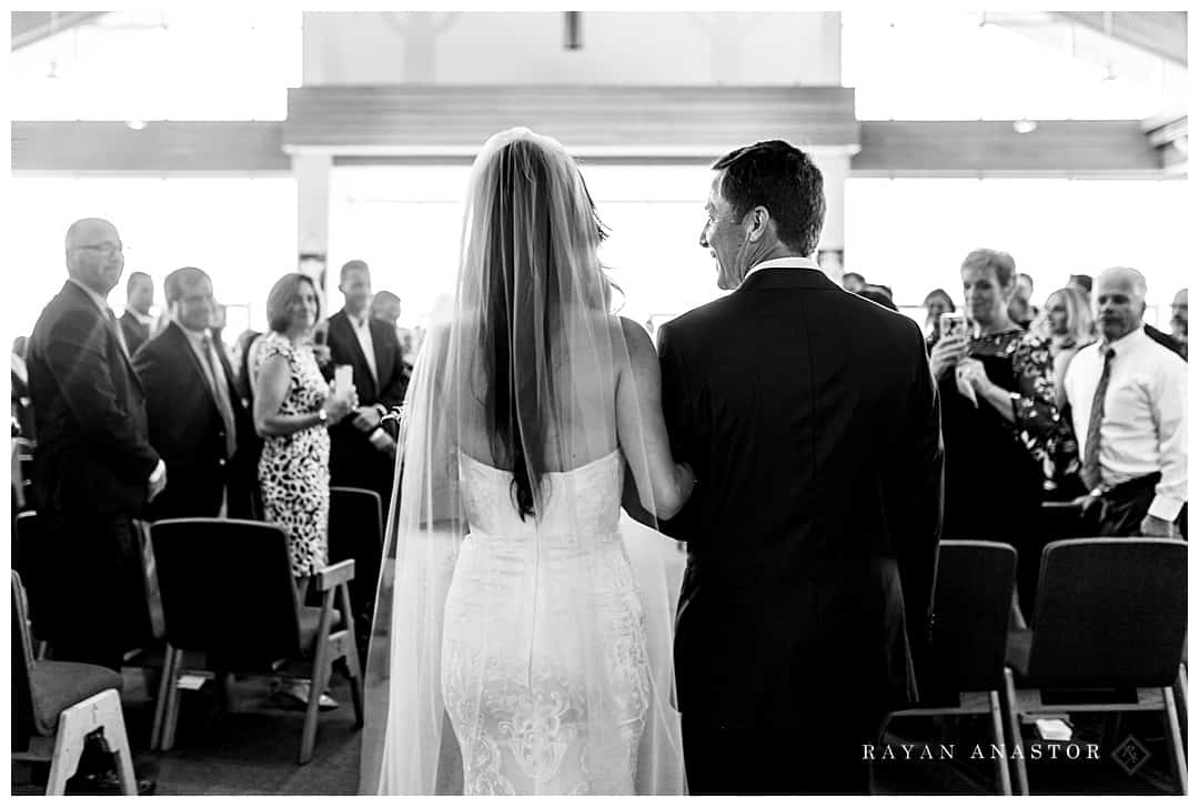 father of bride smiling at bride as she walks down the aisle