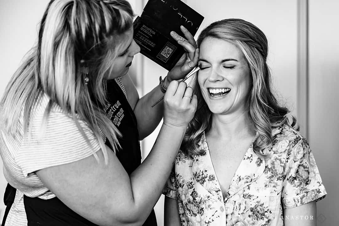bride laughing while having makeup done
