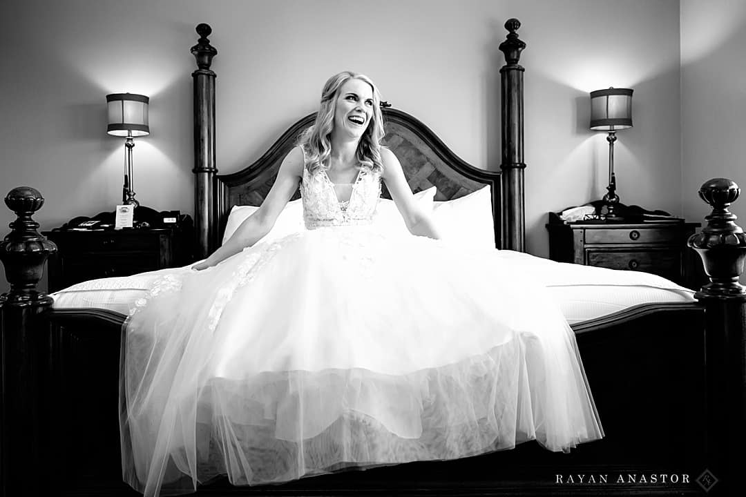 bride laughing after sitting on the bed.