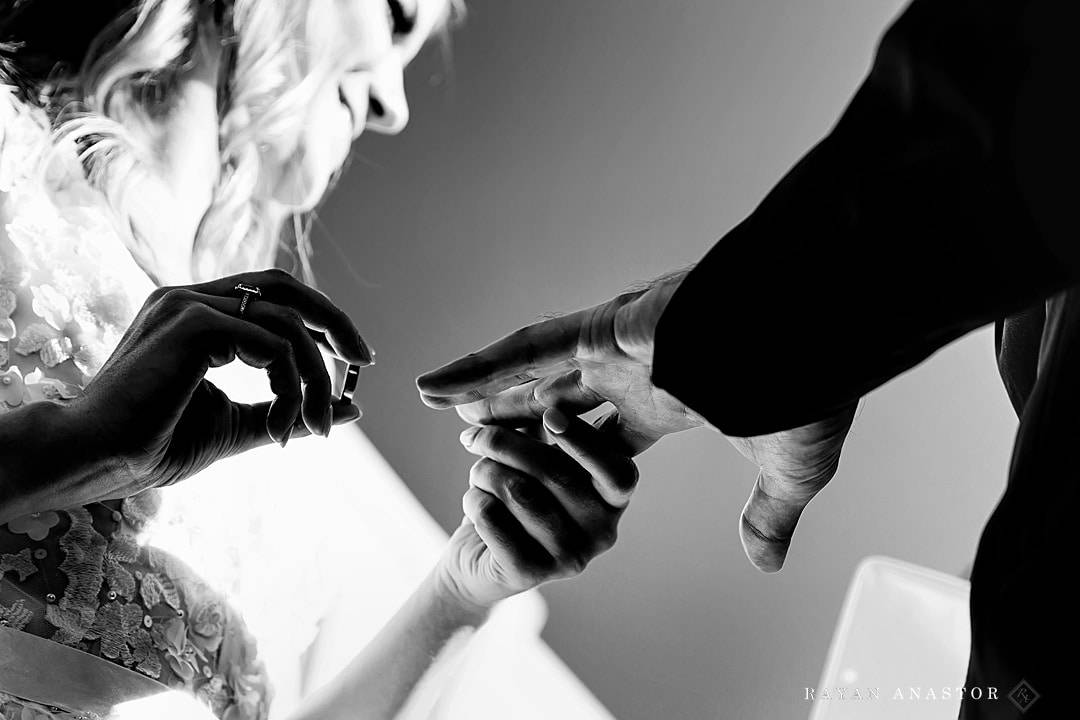 bride putting on wedding band during ceremony