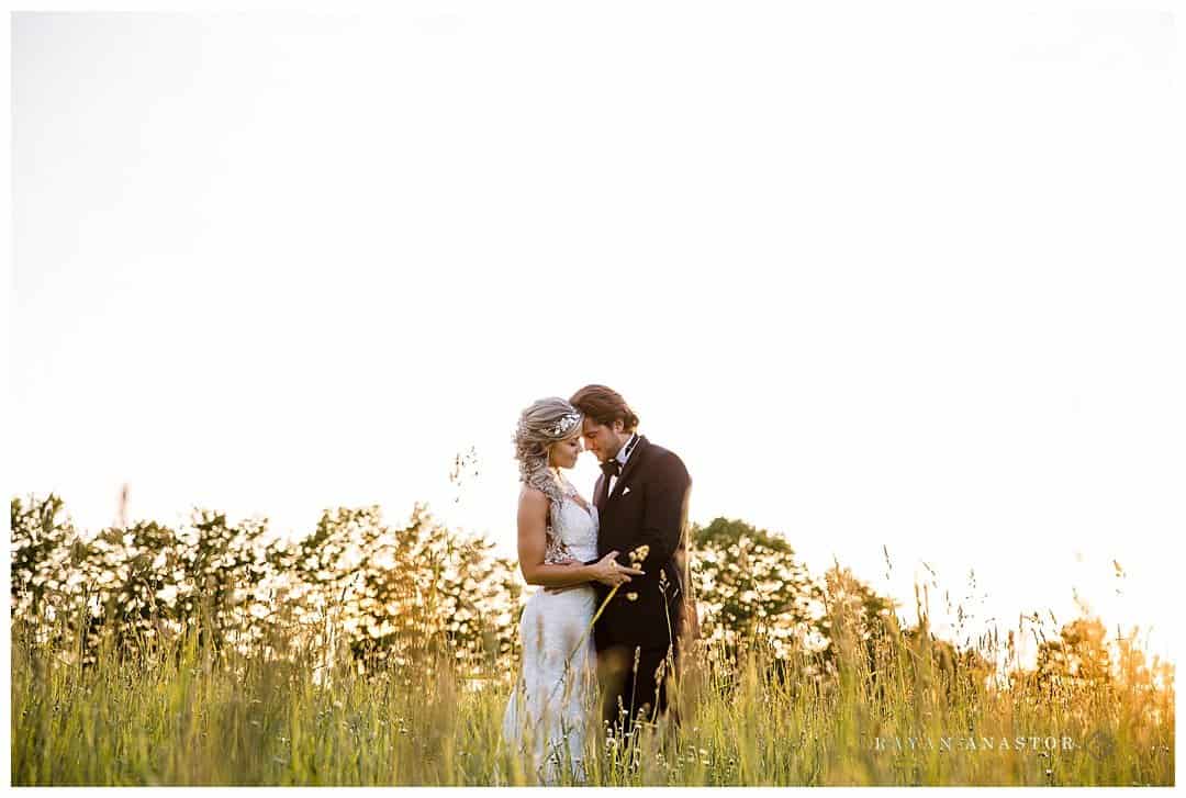 bride and groom in a grassy field at sunset