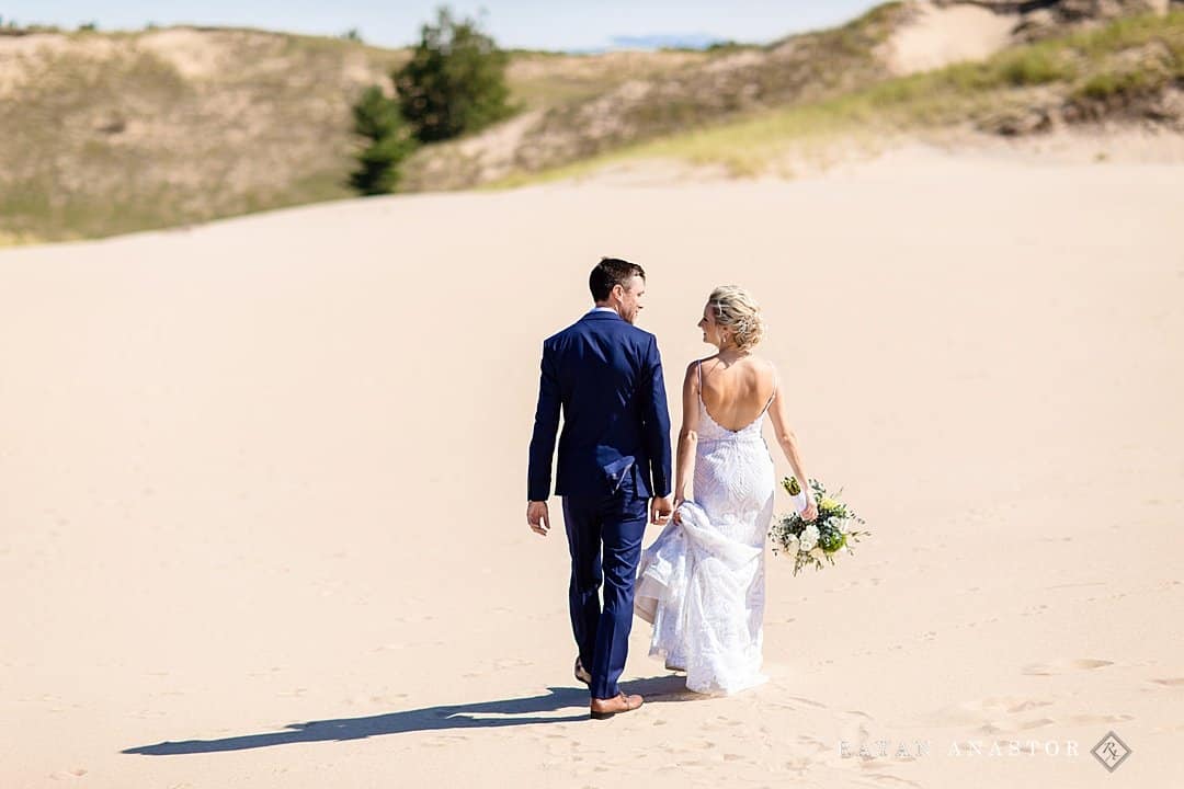 bride and groom walking in the dunes at Crystal Downs