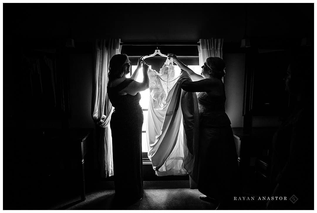 mom and sister getting dress ready for bride