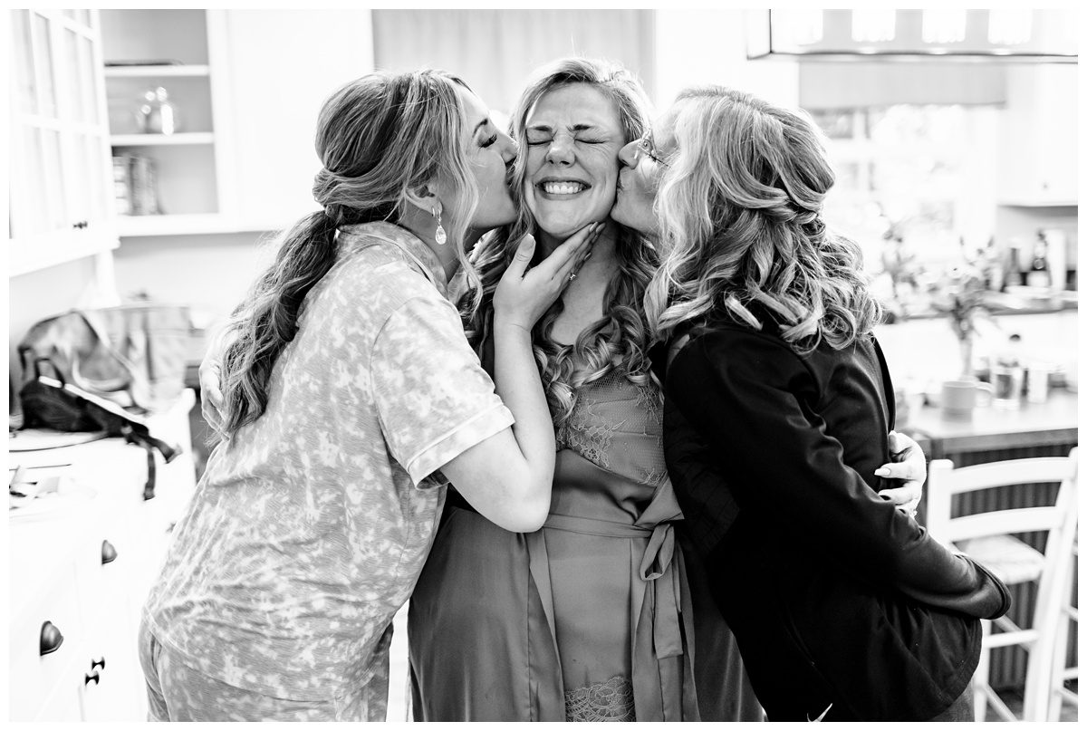 mom and sister kissing bride